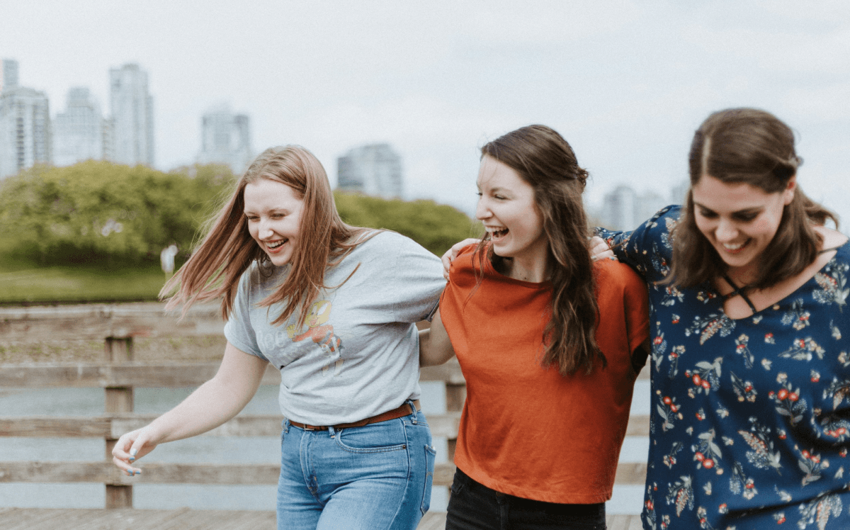 Three women laughing with the city skyline behind them