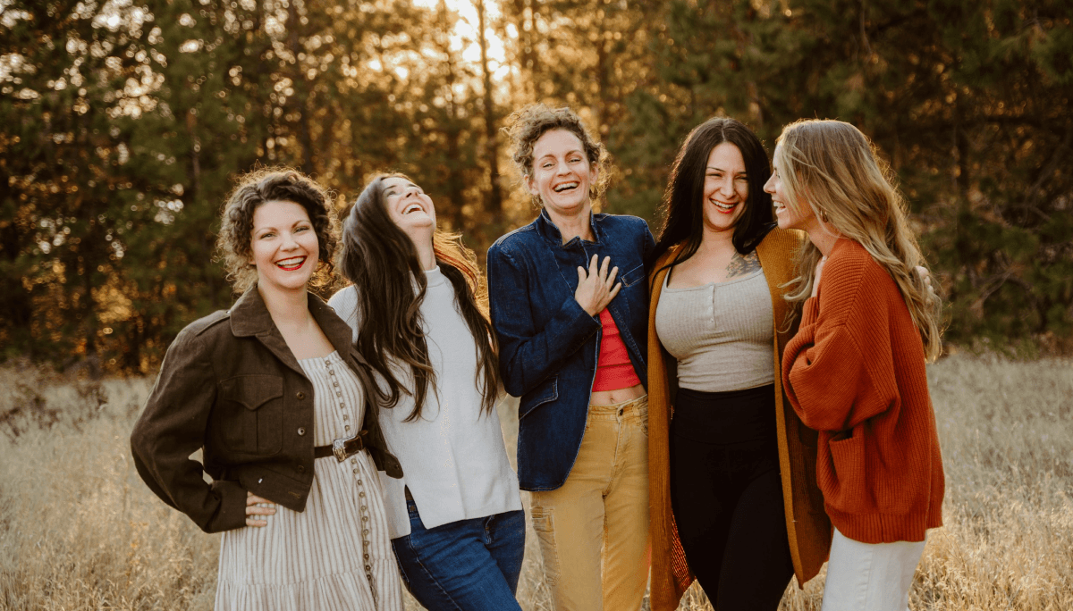 5 women wearing different colors, laughing together