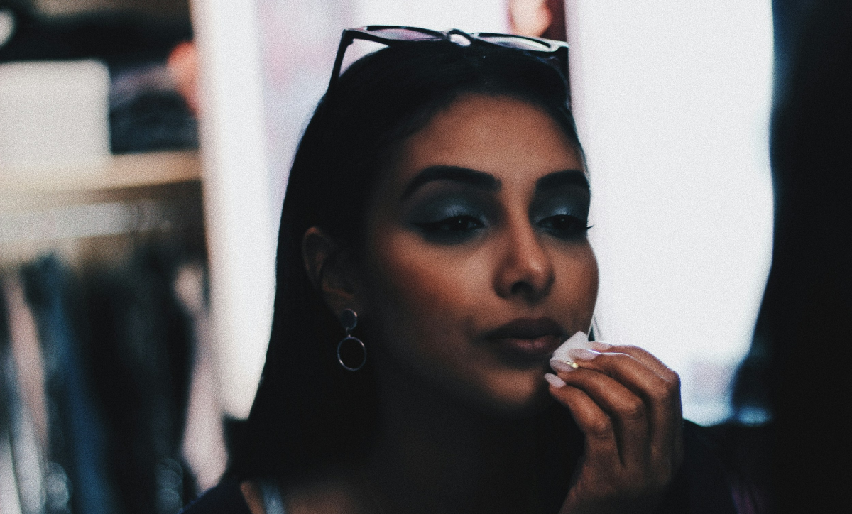 Woman applying makeup in mirror